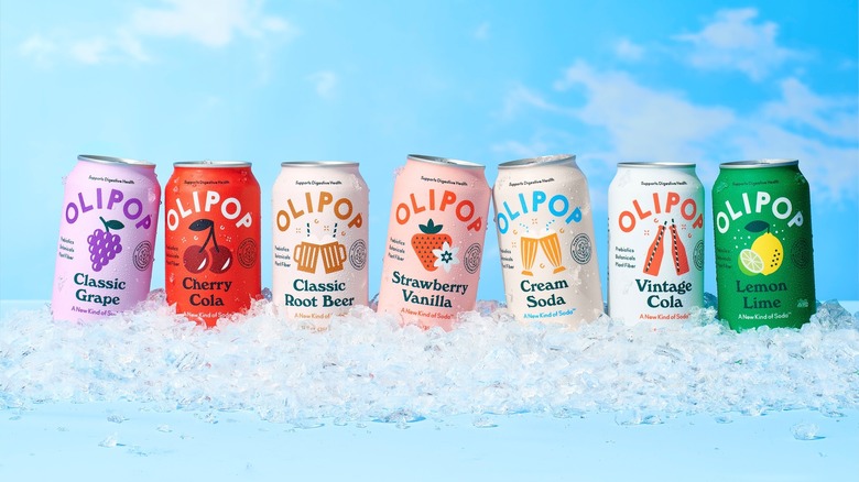 different flavors of Olipop soda on a pile of ice with a blue sky background
