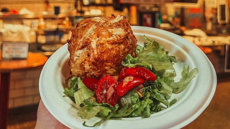A jumbo lump crab cake from Faidley Seafood in Baltimore served on a paper plate with salad