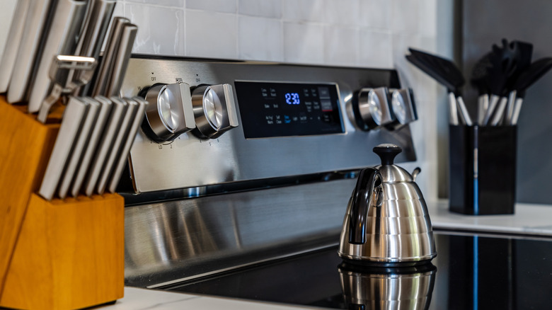 A water heater on an electric range stove with utensil sets on each side
