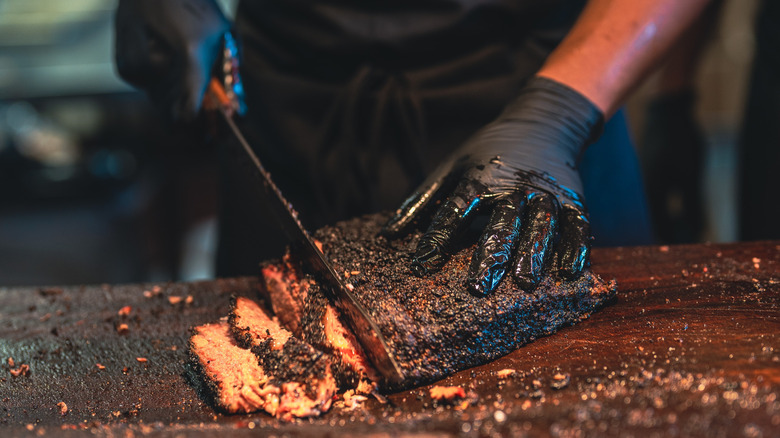 man cutting into smoked brisket on a board