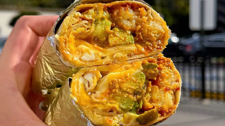 A person holding a Bronco Burrito at Bad-Ass Breakfast Burritos