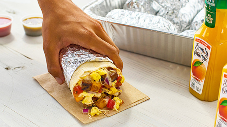 A person holding a breakfast burrito from Qdoba