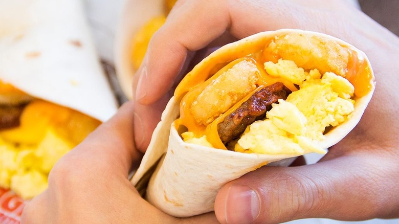 A person holding an Egg-Normous Breakfast Burrito at Burger King