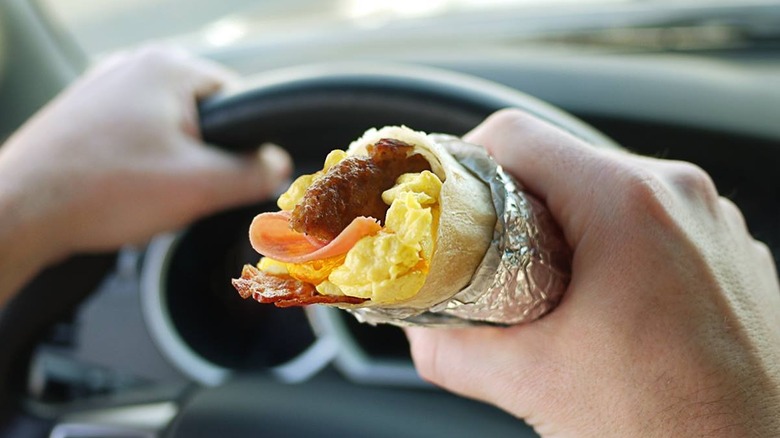 A person holding a Meat Lovers Burrito from Jack in the Box
