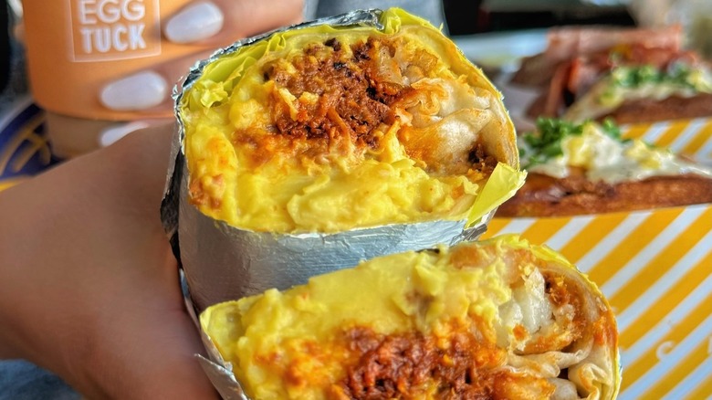 A person holding a Plantspired Egg Burrito from Egg Tuck