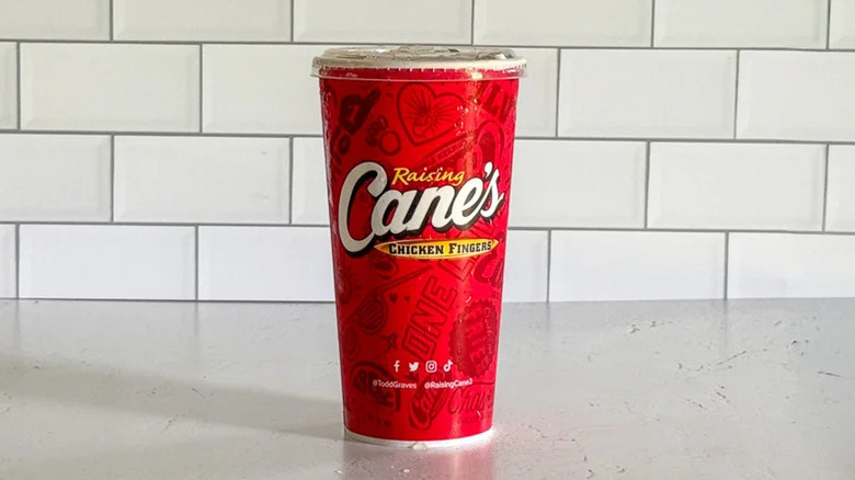 A to-go cup of Raising Cane's sweet tea sitting on a white table