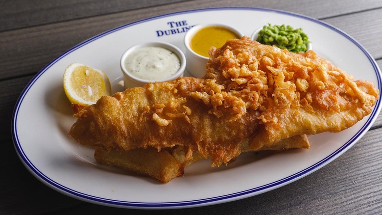 A plate of fish and chips with mushy peas and condiments at The Dubliner