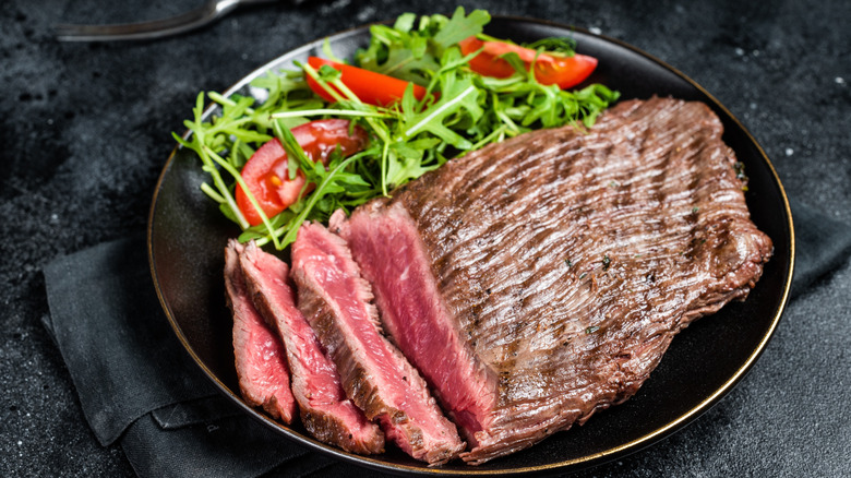 Flank steak with salad on a plate.