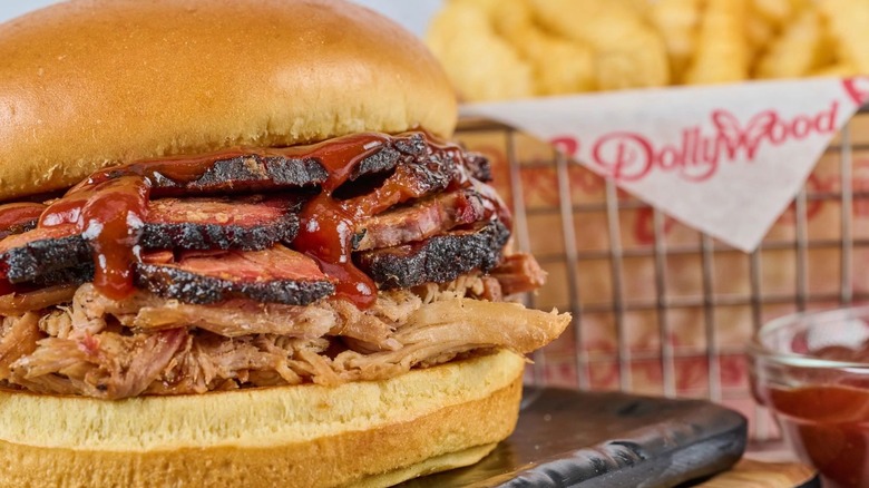 A brioche bun filled with shredded pulled pork, beef brisket, and barbecue sauce