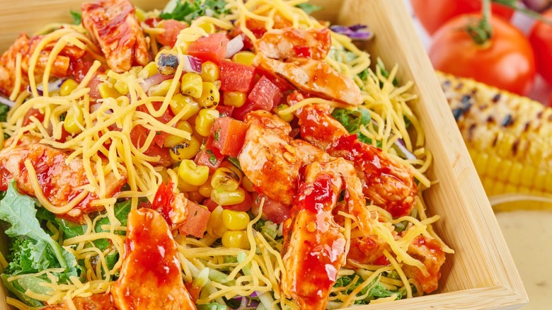 A colorful salad of kale greens, chili-glazed chicken, cheddar cheese, corn salsa, and vinaigrette