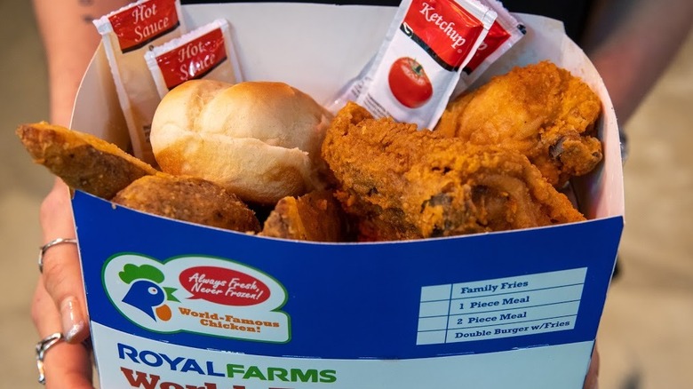 person holding box of Royal Farms fried chicken
