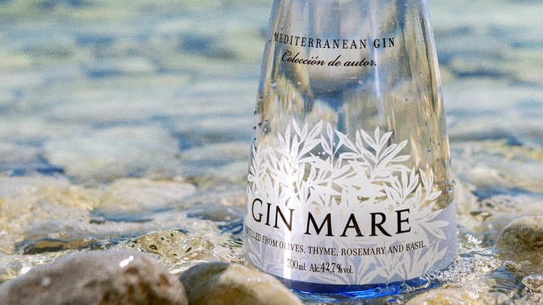 Close-up of the label on a bottle of Gin Mare Mediterranean Gin surrounded by rocks in a pool of water