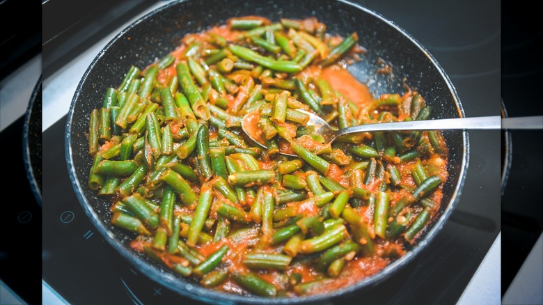 a close up of green beans in tomato sauce