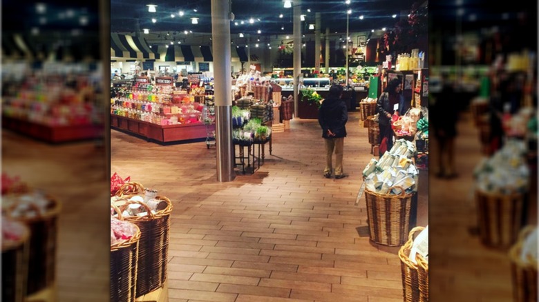 Interior of The Fresh Market with one person, back to camera, standing next to another person near shelves