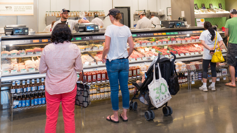 Sign reading "Meat + Poultry" with a cow graphic at a Whole Foods meat department