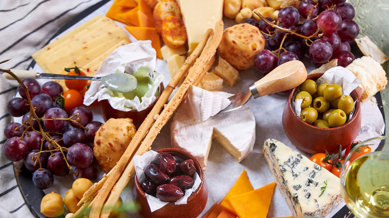 A charcuterie board with meat, crackers, and cheese on a concrete counter