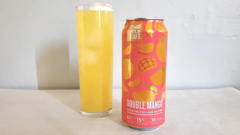 Double mango extra-fruited hard seltzer can with a filled glass