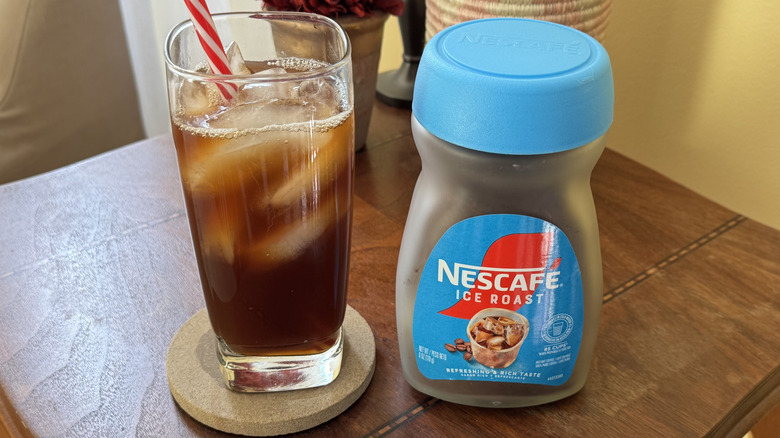 A glass of iced coffee sitting next to a cannister of Nescafe Ice Roast