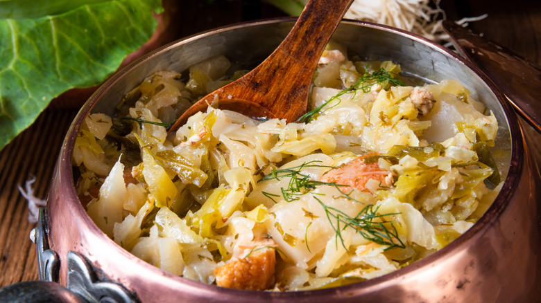 Stewed or sautéed cabbage in a pot with chunks of bacon.