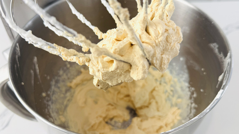 beige frosting in a metal bowl