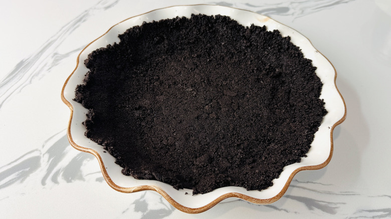 chocolate cookie crumbs in a white pie plate
