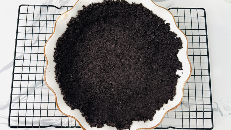 chocolate cookie crumbs in a white pie plate on a wire rack