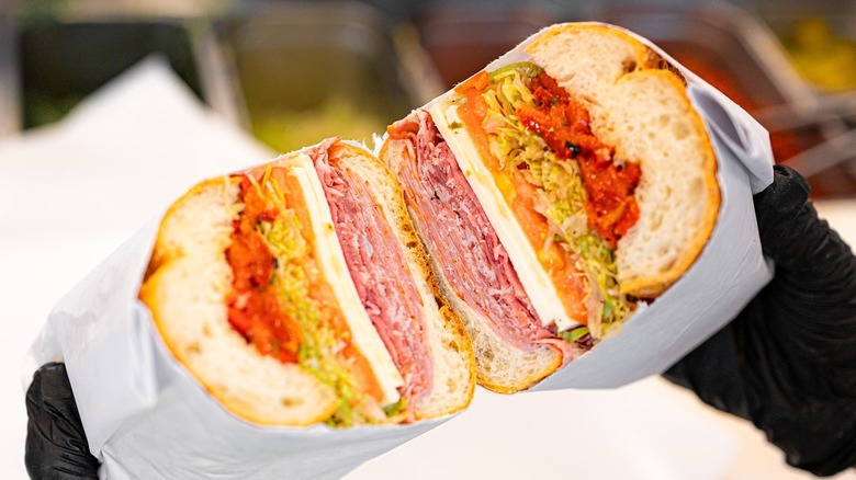 A person holding an Italian sandwich at Faicco's Italian Specialties in New York City
