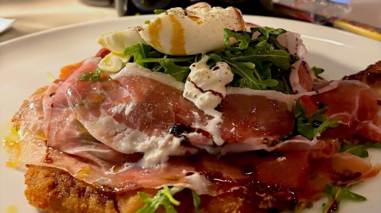 An appetizing breaded veal topped with prosciutto and arugula.