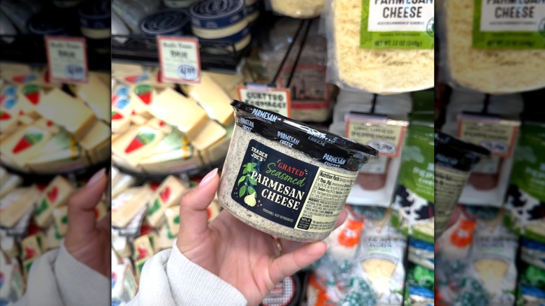 Hand holding container of Grated Seasoned Parmesan Cheese.