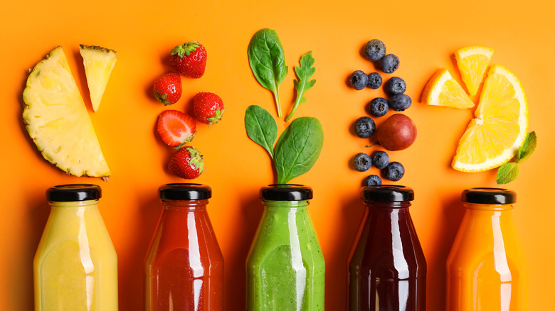 different colored juice bottles with fresh ingredients