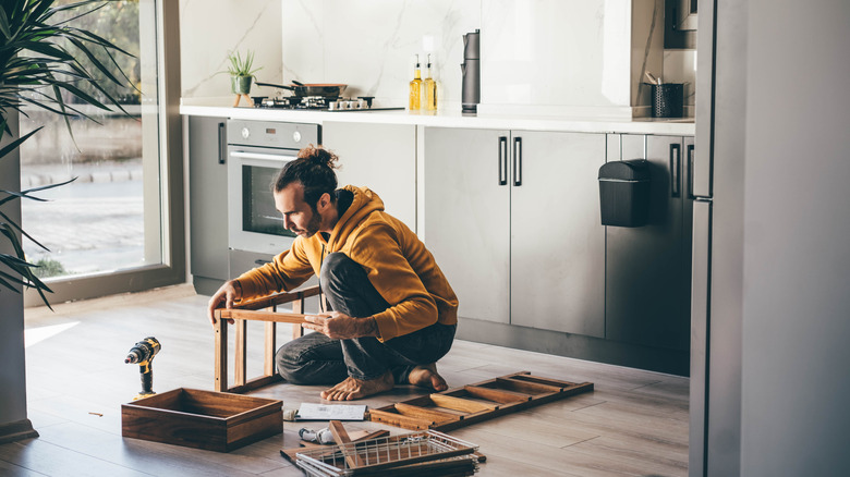 Man assembling furniture in kitchen