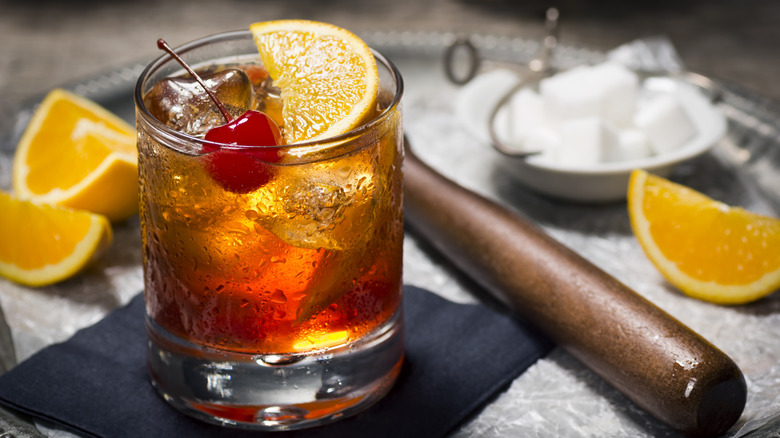 Old fashioned cocktail with orange and cherry garnishes