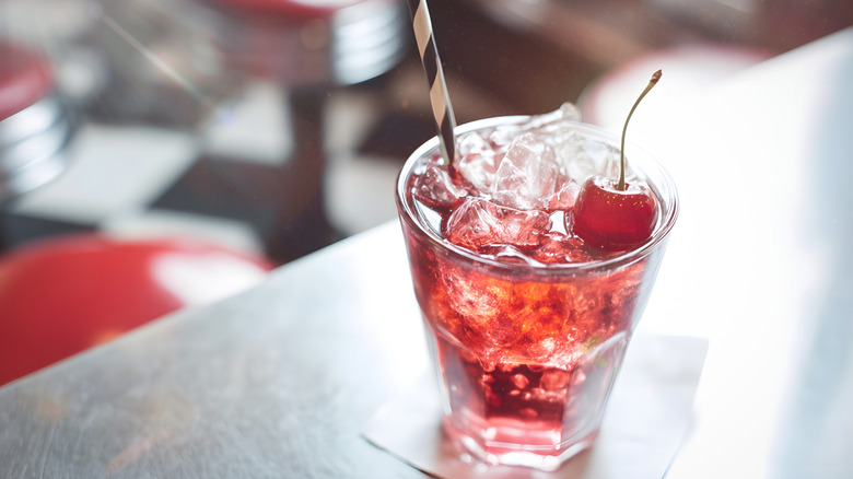 Cherry soda cocktail with a white and black striped straw