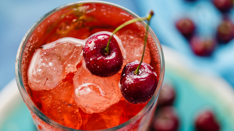 Overhead view of a glass of cherry soda with fresh cherries as a garnish