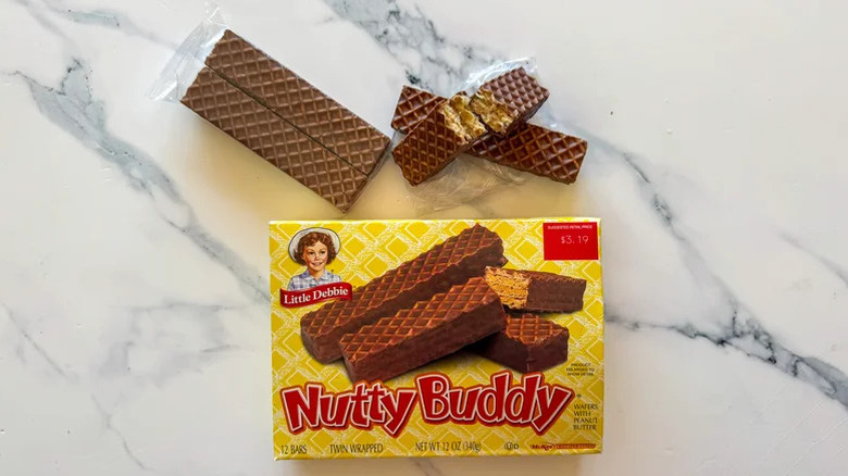 A pack of Little Debbie Nutty Buddy with the wafers laid out against a marble background