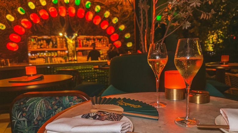 Two champagne flutes at Amazonico with bar in background