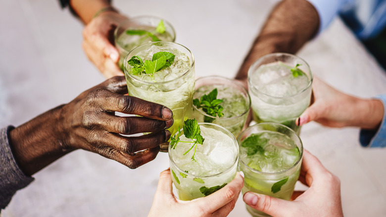 Several people clinking their glass of mojito