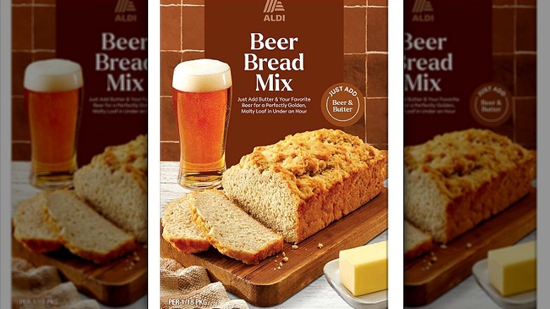 A beer bread mix in a box that shows a glass of foamy beer, a partly sliced loaf, and a block of butter.
