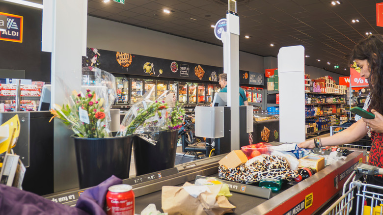 Customers putting groceries on checkout conveyor belt at Aldi
