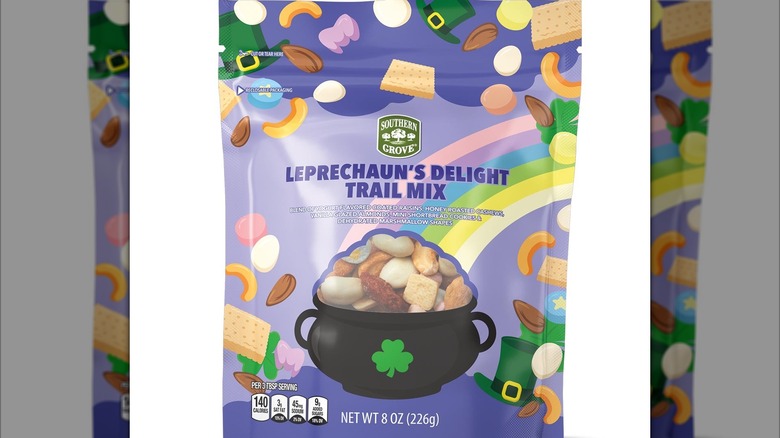A colorful package of Leprechaun's Delight Trail Mix with a small clear window showing the product inside, cut out in a fun shape that makes it look like it's inside a black cauldron with a four-leaf clover.