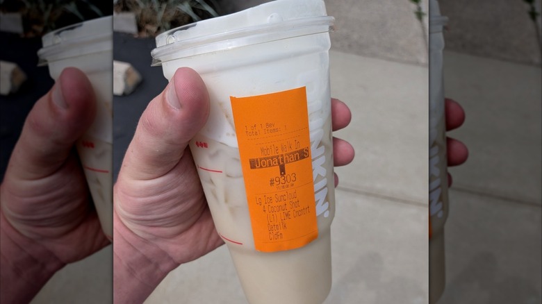 Person holding Coconut Limeade in a large plastic Dunkin' cup