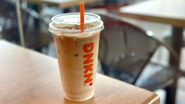 A Dunkin' drink sits on a wooden table