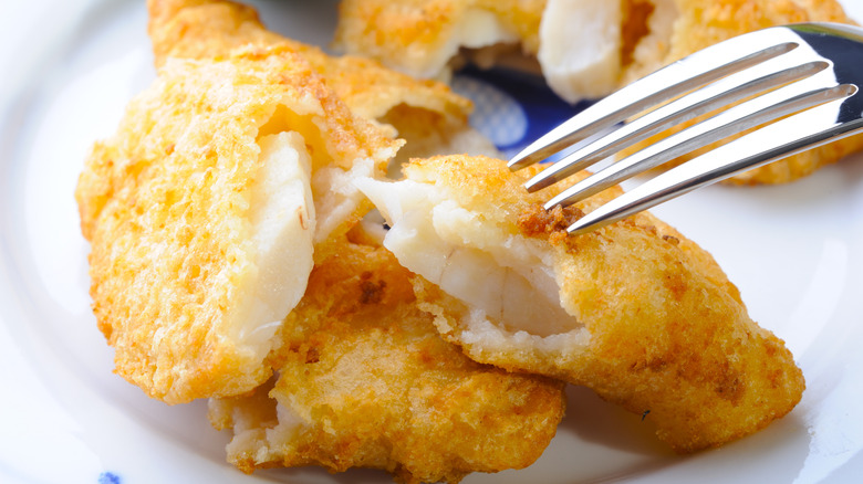 Deep-fried cod on a white plate.