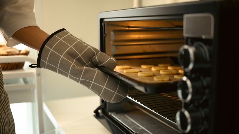 Oven mitt pulling tray out of oven