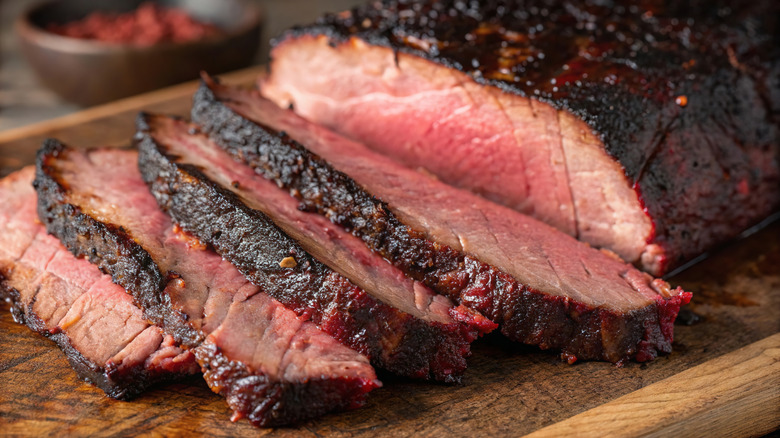 Sliced brisket is arranged on a cutting board.