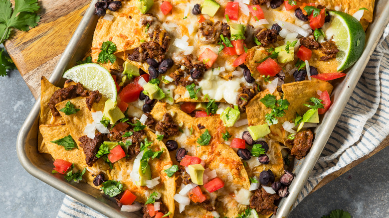 Homemade Mexican beef birria nachos with cheese beans and avocado.