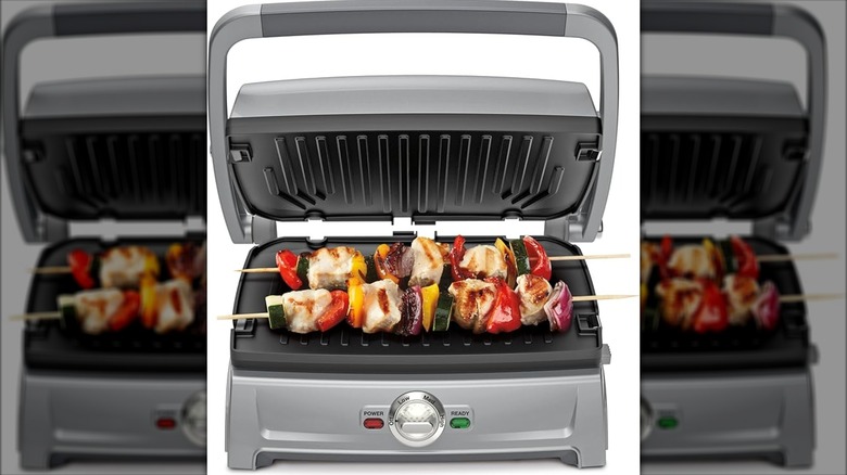 A panini press has kabobs on it.