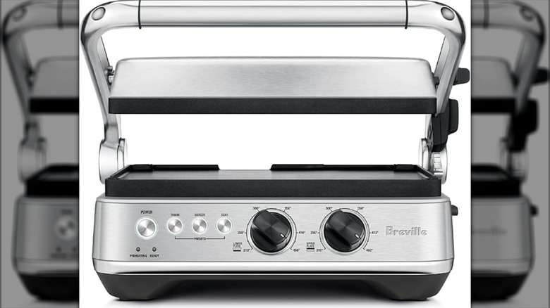A panini press has dials and buttons on the front.