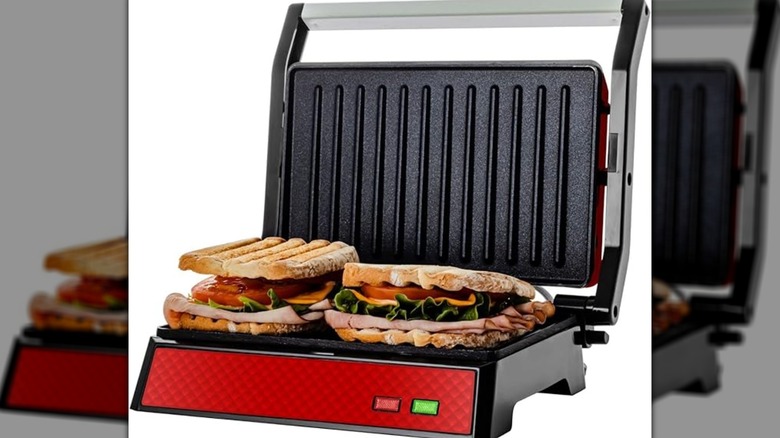 An open panini press has sandwiches on it.