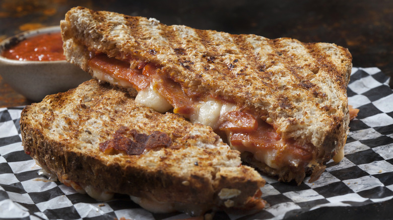 A pepperoni pizza style panini sandwich is cut in half.
